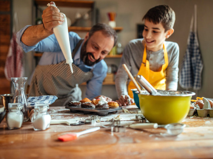 Photo of father and his son decorating cupcakes in the kitchen