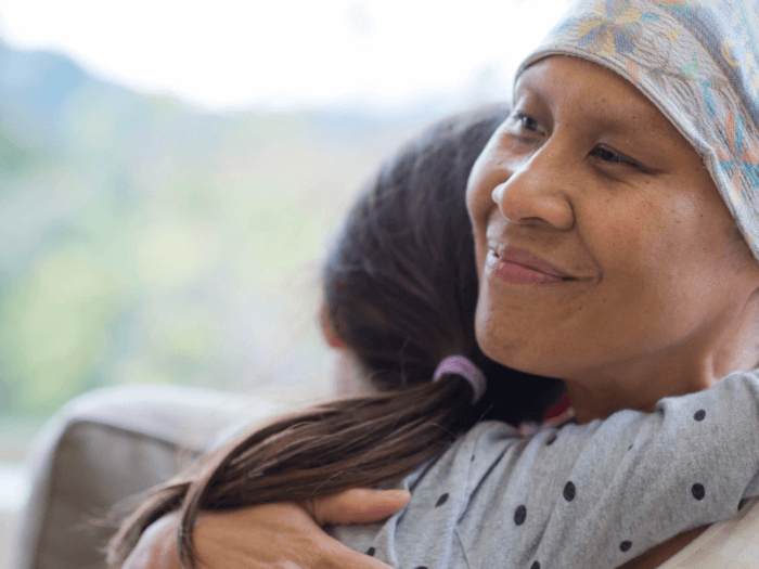 Ethnic adult female cancer patient hugging her granddaughter 1