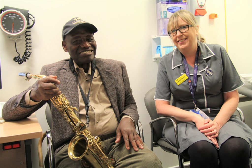Rex at Guys Cancer Centre with his saxophone sat with Louisa Fleure, Lead Uro-Oncology Clinical Nurse Specialist