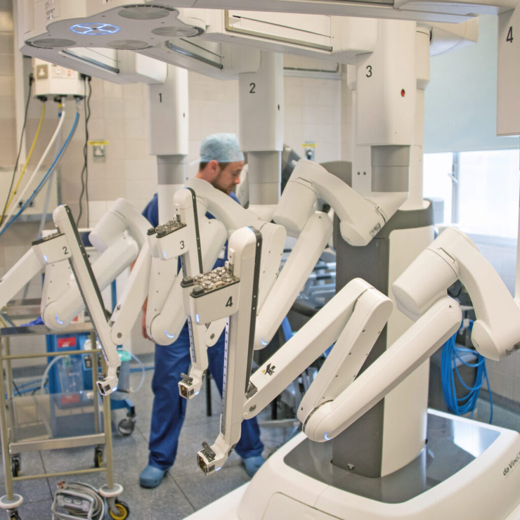 Robotics machine, labelled with numbers 1, 2, 3 and 4. Member of staff behind dressed in all blue wearing a light blue hair net operating the machinery.