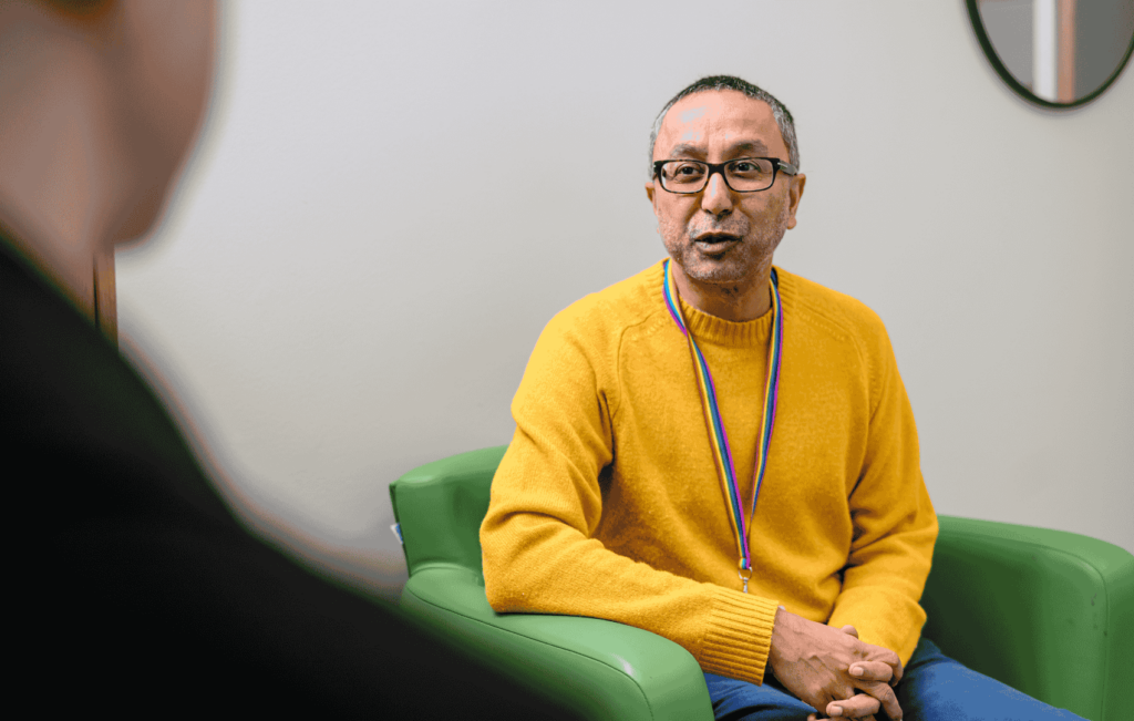Nazim sat in a yellow jumper appearing to be listening to a Guy