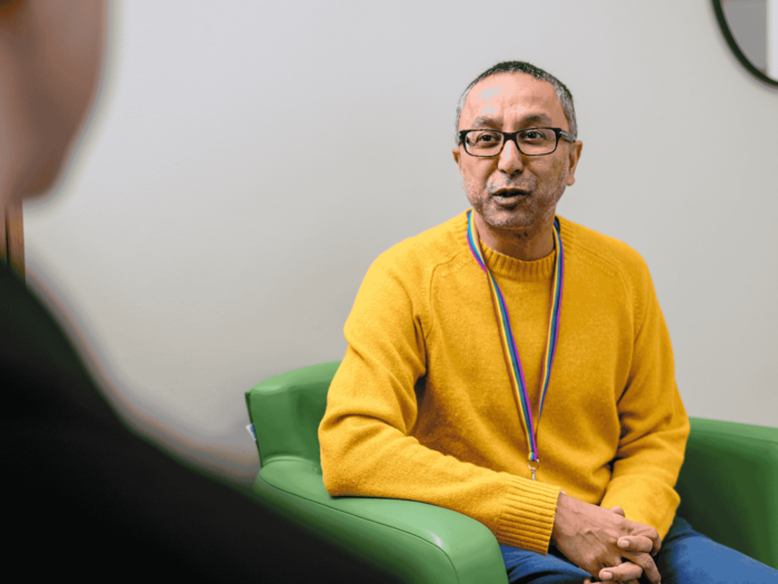 Nazim sat in a yellow jumper appearing to be listening to a Guy